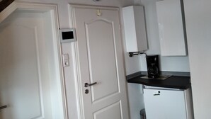 A kitchen with white cabinets, a coffee maker, and a clock on the wall.