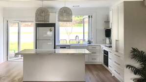 A modern kitchen with a central island, white cabinetry, and pendant lighting. - Rye Beach Escape (Rye)