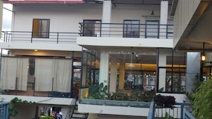 A multi-story building with a glass facade, outdoor seating, and a staircase leading to an upper level. - Kalash Parkaze and Tent Inn (Pokhara)