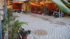 A courtyard with potted plants, a motorcycle, and a seating area with tables and chairs. - Kalash Parkaze and Tent Inn (Pokhara)