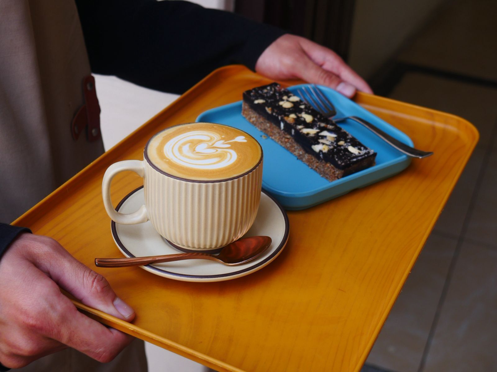 A tray with a cup of coffee and a piece of cake.