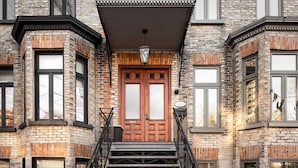 A building with a prominent wooden door, a staircase, and multiple windows. - Villa Montcalm: Prestige & Confort au Vieux-québec (Québec)