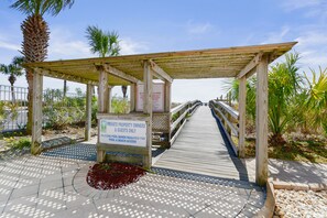 A wooden boardwalk leading to a covered area with a sign indicating private property access.