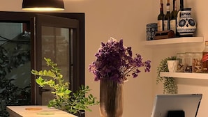 A reception desk with a tablet, a vase with purple flowers, and a shelf with bottles and jars.