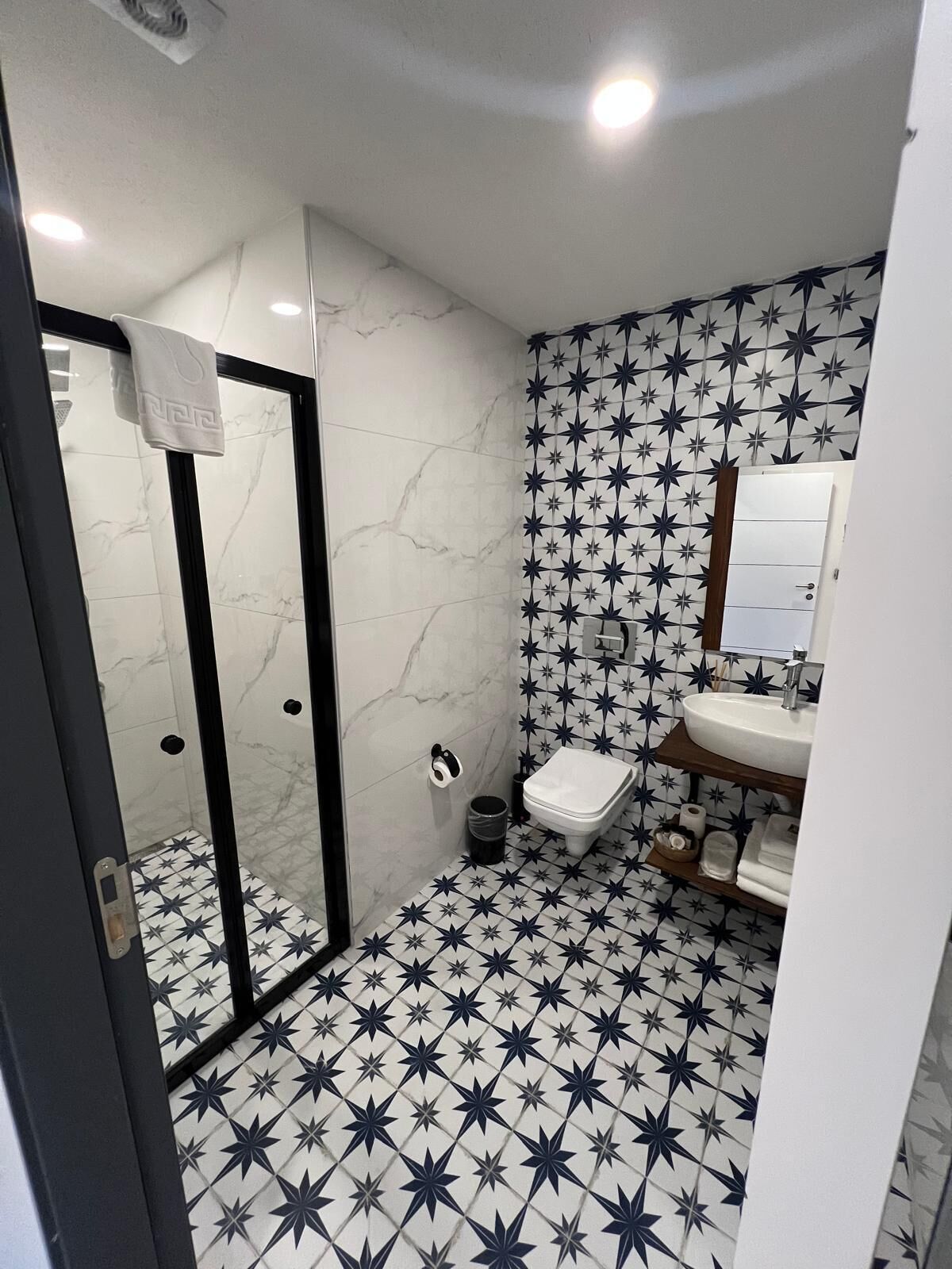 A bathroom with a star-patterned floor, a white toilet, and a sink with a mirror above it.