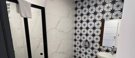 A bathroom with a star-patterned floor, a white toilet, and a sink with a mirror above it.