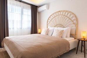 Une chambre à coucher avec un grand lit, une tête de lit ronde, une lampe de chevet et un appareil de climatisation fixé au mur.
