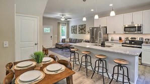 Una cocina moderna con una isla central, electrodomésticos de acero inoxidable y taburetes de bar.
