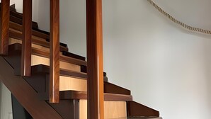 A wooden staircase with a handrail and a white wall in the background. - Cozy holiday home in the heart of Versilia (Viareggio)