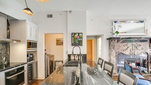 A modern kitchen with stainless steel appliances, a marble countertop, and a dining area with a large table and chairs. - Luxe Long Beach Condo w/ Pool: 1 Mi to Shoreline! (Long Beach)