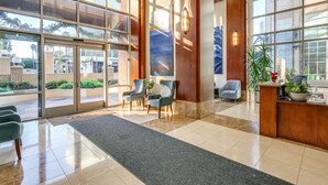 A modern hotel lobby with large glass doors, a reception desk, several chairs, and a potted plant. - Luxe Long Beach Condo w/ Pool: 1 Mi to Shoreline! (Long Beach)
