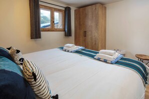 Een slaapkamer met een groot bed, een houten garderobe en een raam met gordijnen.