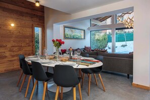 A dining area with a round table set for six, surrounded by black chairs with wooden legs. - Chalet Gloribel, ski, views, Chamonix All Year (Chamonix)