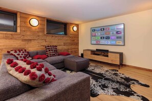 Een moderne woonkamer met een hoekbank, een flatscreen televisie aan de wand en een houten tv-meubel.