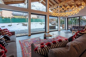 A spacious living area with a large window overlooking a snowy outdoor deck. - Chalet Gloribel, ski, views, Chamonix All Year (Chamonix)
