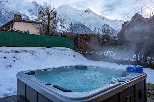 A hot tub in a snowy outdoor setting with mountains in the background.