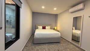 Ein Hotelzimmer mit Bett, Nachttischlampe, Klimaanlage und einem großen Spiegel.