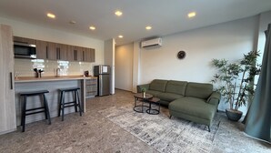 Eine moderne Küche mit einer zentralen Kochinsel, Barhocker, einem grünen Sofa und einem Blumentopf.