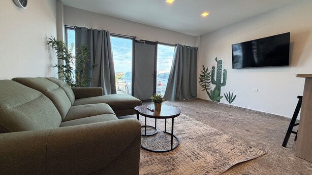 Ein Wohnzimmer mit einer Couch, einem Couchtisch und einem an der Wand befestigten Fernseher.