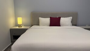 Een hotelkamer met een bed, een nachtkastje met lamp en een stopcontact.