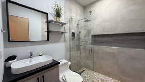 Ein modernes Badezimmer mit großem Spiegel, Waschbecken, Toilette und Duschbereich.