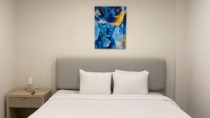 Ein modernes Schlafzimmer mit einem großen Bett, einem Nachttisch und einem an der Wand befestigten abstrakten Gemälde.