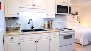 Una cocina moderna con armarios blancos, un lavamanos doble, un microondas y una estufa.