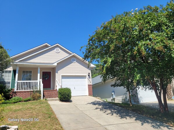 A single-story house with a red door, a garage, and a tree in the front yard. - Clean, Spacious. Newly renovated Garden Home in the heart of Pensacola.  (Pensacola)