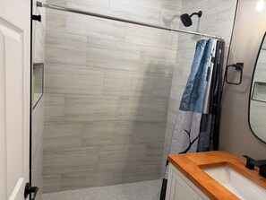 A modern bathroom with a shower, a wooden vanity, and a mirror. - Munds Park - Beautiful Munds Park Suite for Rent. Newly built! (Sedona)