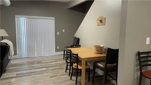 A dining area with a wooden table and chairs, a bench, a lamp, and a 'Welcome to the Cabin' sign on the wall. - Munds Park - Beautiful Munds Park Suite for Rent. Newly built! (Sedona)