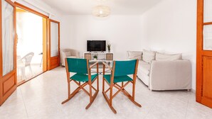 A living room with a TV, sofa, and two green chairs.