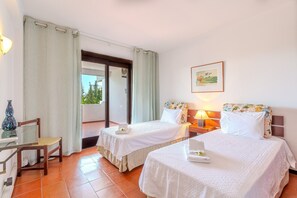 Habitación de hotel con dos camas, un escritorio, una silla, una lámpara y un cuadro en la pared.