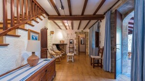Un intérieur rustique avec un escalier en bois, des murs en pierre, une cheminée et un coin repas.