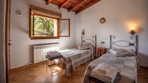 A bedroom with two beds, a window, a radiator, and a wooden ceiling. - Villa Simone in Town, Pool and Wifi with private pool, Wi-Fi and air conditioning (Pollensa)