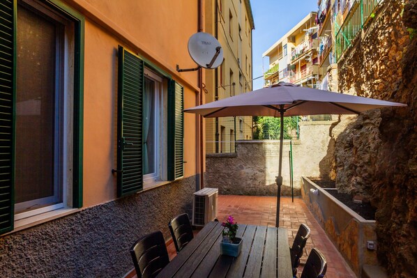 An outdoor patio with a table, chairs, and a satellite dish.