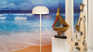 Una habitación con un mural de playa, una lámpara y una figura de jirafa.