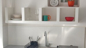Una cocina con un lavamanos, un reloj y una ventana con persianas.
