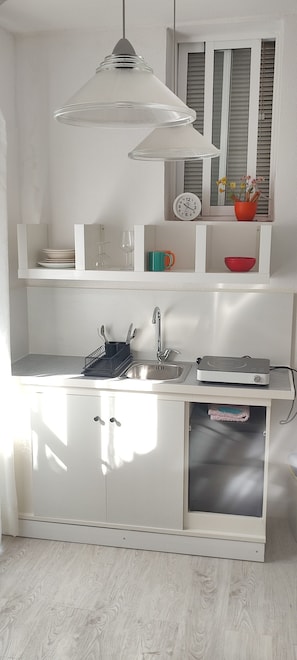 A kitchen with a sink, a clock, and a window with blinds.