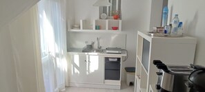 Una cocina compacta con un lavamanos, un tostador y un armario pequeño.