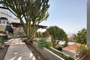 Jardim no terraço com cactos, um deck de madeira e vista para o oceano.