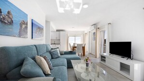 Una sala de estar moderna con un sofá, televisor y una mesa de centro de vidrio.
