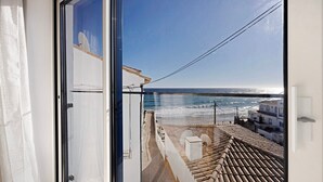 Un balcón con vista al mar, techo de tejas y pared blanca.