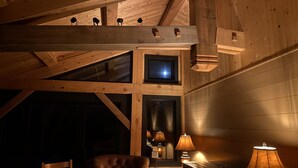 A cozy cabin interior with a loft bed, a leather armchair, and multiple lamps. - Dragonfly - Unique, tranquil retreat in Grand Marais, MN (Grand Marais)