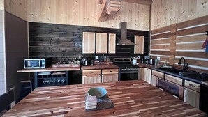 A modern kitchen with wooden cabinetry, a central island, and a built-in oven. - Dragonfly - Unique, tranquil retreat in Grand Marais, MN (Grand Marais)