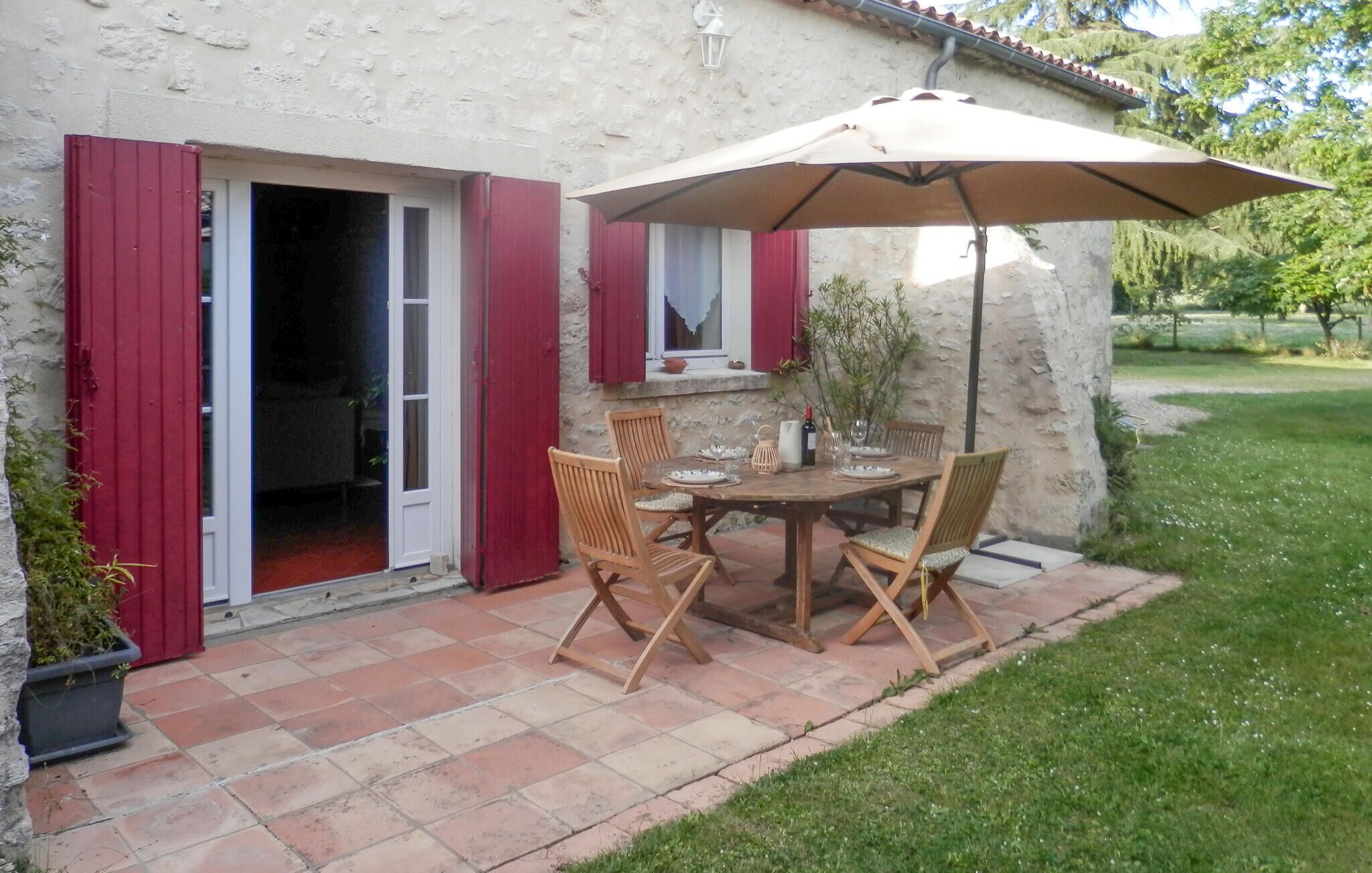 An outdoor patio with a table and chairs, a large umbrella, and a stone wall.