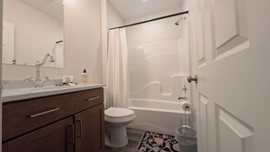 Ein Badezimmer mit Toilette, Dusche, Waschbecken und Spiegel sowie einem Schrank.