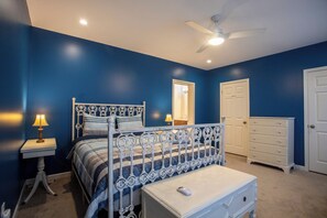 Ein Schlafzimmer mit einem Bett, einem Nachttisch, einer Kommode und einem Deckenventilator.