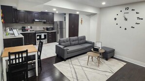 A modern apartment with a kitchen, dining area, and living room. - Zen Nest - Cozy, conveniently located, and just minutes to the airport! (Brampton)