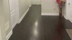A hallway with dark wooden flooring, white walls, and a white door at the end. - Zen Nest - Cozy, conveniently located, and just minutes to the airport! (Brampton)