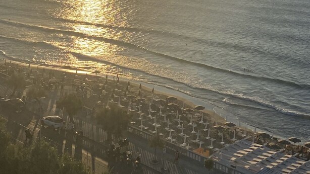Vista costera con playa y zona de estacionamiento con sombrillas.